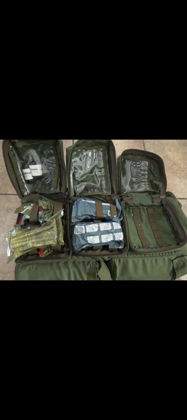 Mochilas tácticas verdes abiertas mostrando equipo médico y de trauma organizado por compartimentos