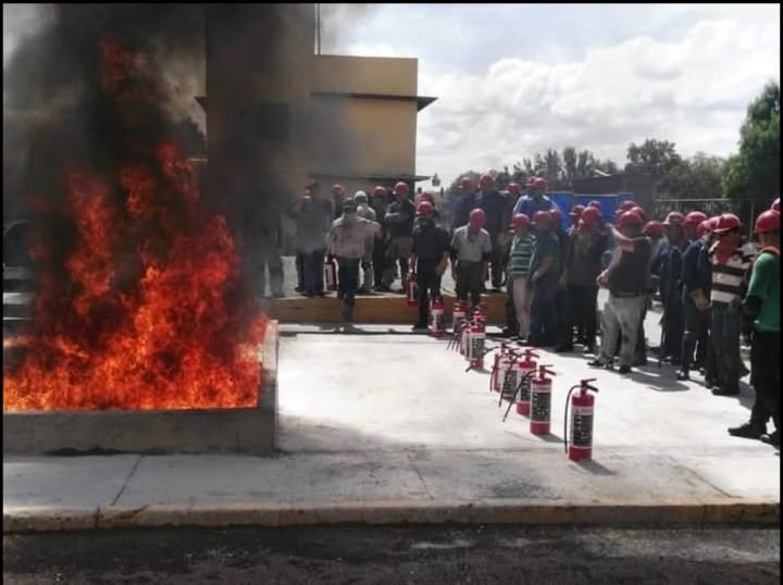 Grupo formado junto a extintores frente a un fuego controlado de gran tamaño