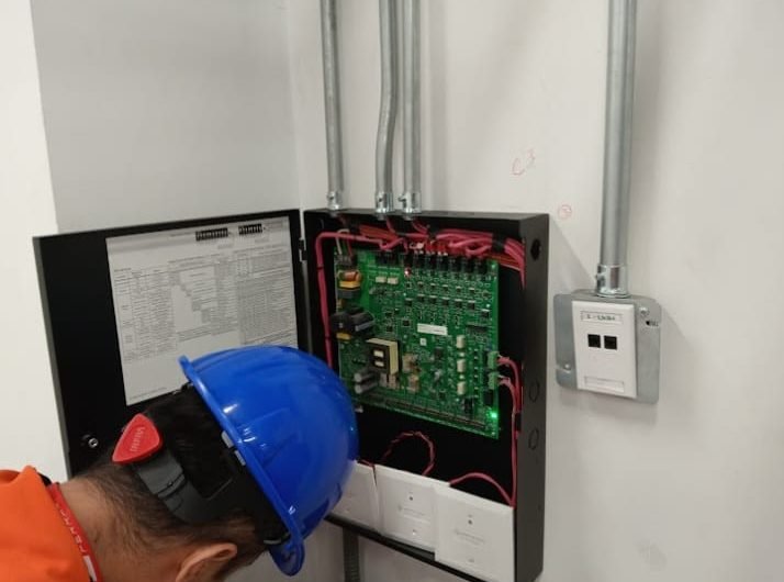 Técnico revisando la tarjeta electrónica de un panel de alarma contra incendio